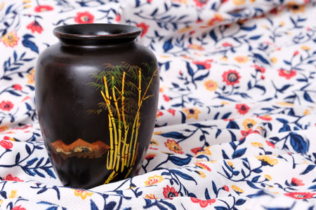 Vietnamese black lacquer vase with hand painting isolated on floral fabric backgroundの写真素材