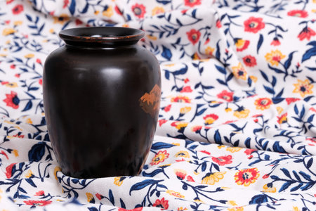 Vietnamese black lacquer vase with hand painting isolated on floral fabric backgroundの写真素材