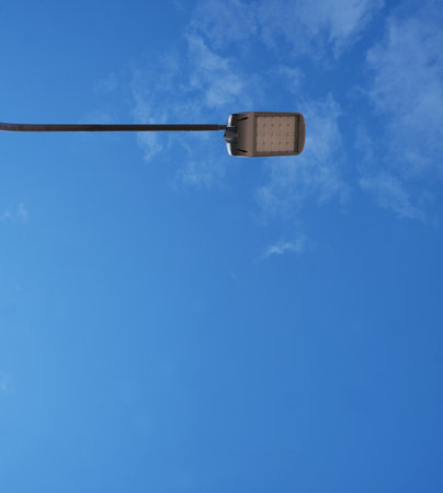 Isolated blue sky with white clouds and a street lamp on a sunny dayの写真素材