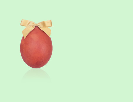 Easter poster template. Natural egg and with a golden bow isolated on green backgroundの写真素材