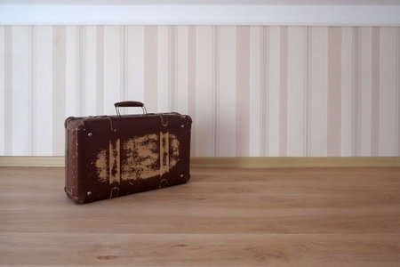 Old suitcase isolated on the floor in an empty roomの写真素材