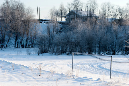Winter village landscape with snow-covered houses and trees under blue skyの写真素材
