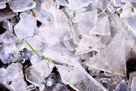 Ice fragments on frozen lake water level. The ice broken into shinning jagged pieces. Dark natural backlight.の写真素材