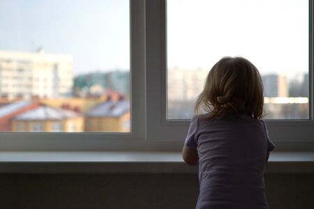 A little girl standing in front of a window. High quality photoの写真素材