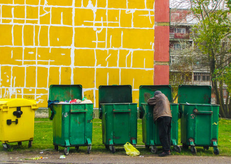 Poor man looking for food in a waste containerのeditorial素材