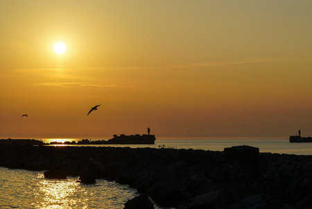 beautiful sunset by the breakwater port pierの写真素材