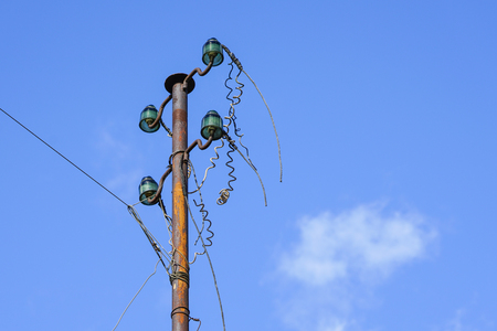 old electric pillar with glass insulators and disconnected wiresの写真素材