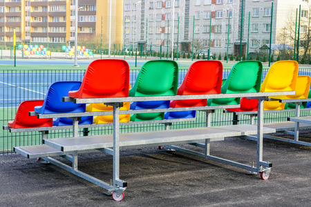 portable small size metal stands with colorful plastic seats for spectators in the stadiumの写真素材
