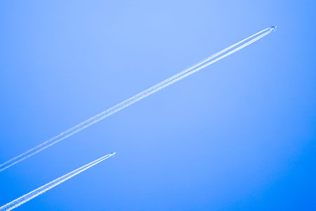 Two planes flying high in the sky in one direction, leaving white streaks