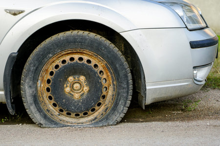 silver color car with flat tire on old rusty rim