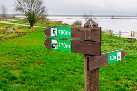 wooden direction indicator in the park with pictograms and distance signs in metersの写真素材