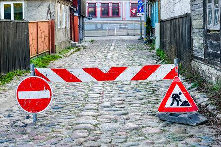 road barrier with warning and prohibition road signs on an old paved streetの写真素材