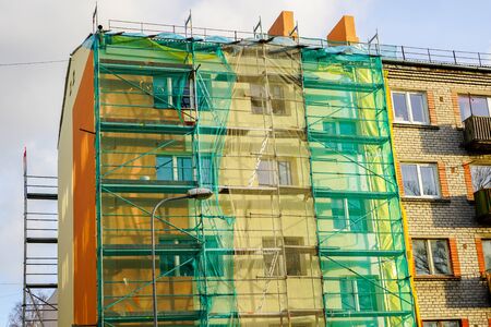 scaffolding arround the house to install thermal insulation of the apartment building facade, blue sky backgroundの写真素材