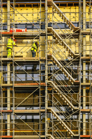 scaffolding arround the house to install thermal insulation of the building facade, workers in safety vests and helmetsの写真素材