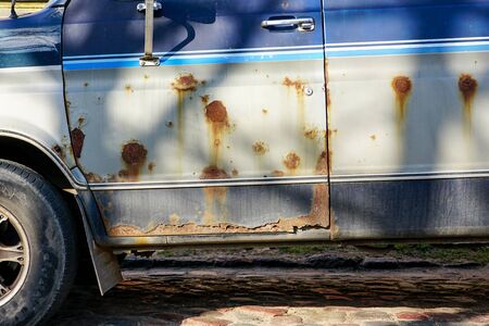 a fragment of a very rusty car body on a city streetの写真素材