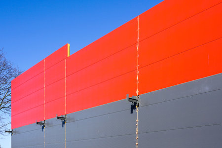 the wall of the metal frame building, covered with sandwich panels in red and gray