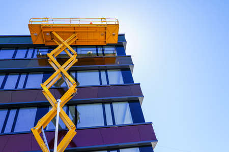 modern building facade repair using a high scissor lift with a platformの写真素材