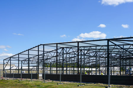 construction of a new modern industrial building, metal truss frame on a background of blue sky