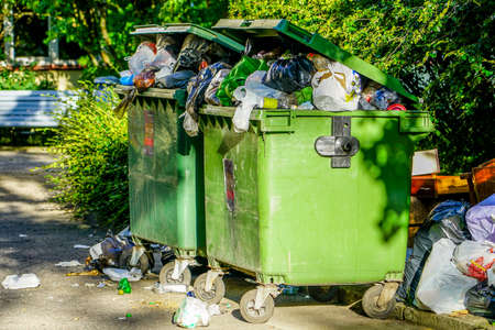 two crowded green plastic waste containers in the cityの写真素材