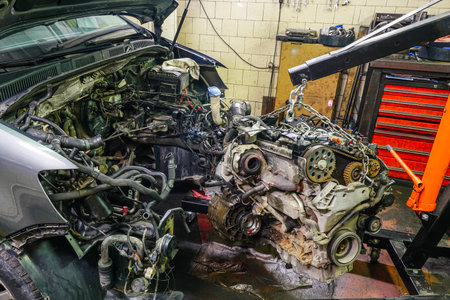 dismantling a damaged engine from a car with the help of a folding hydraulic crane