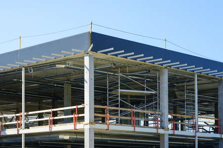 unfinished metal frame of a new modern industrial building with utilities against a blue skyの写真素材