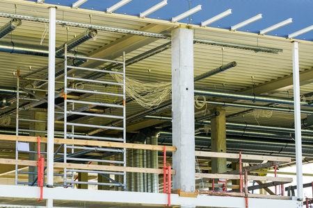 unfinished metal frame of a new modern industrial building with utilities against a blue sky