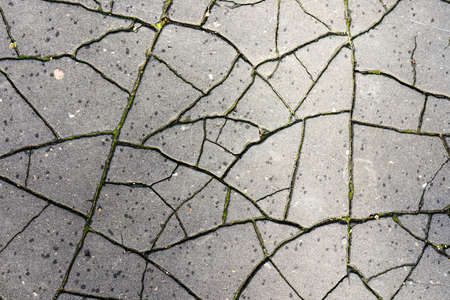worn and cracked in many small fragments old asphalt surface backgroundの写真素材