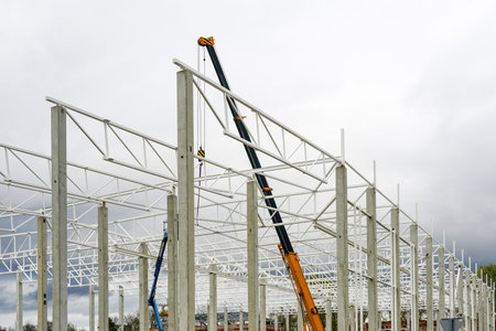 a crane with a telescopic boom in the assembly of metal structures in a new modern industrial...