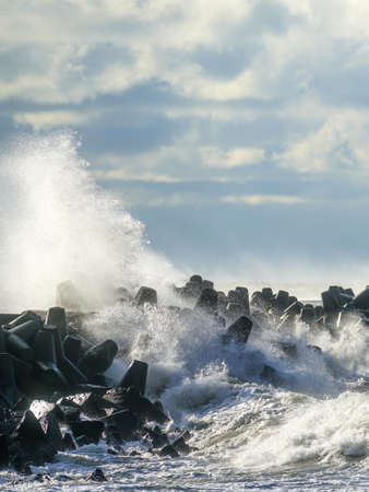 coastal storm in the Baltic Sea, big waves crash against the concrete breakwater at the port entranceの写真素材