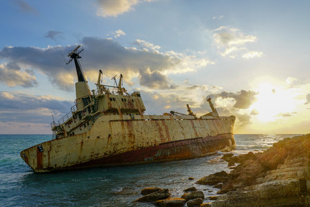 a large old rusty shipwreck on a rocky coast against a beautiful sunset background