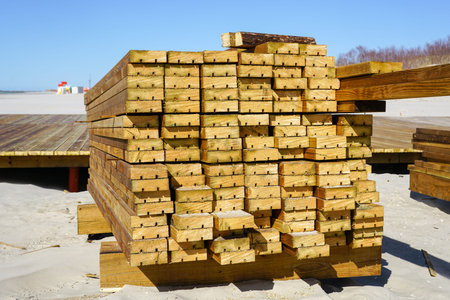 End view of stacked brown pine wood outdoor decking boards for sandy beach infrastructure...