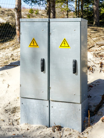 Two new galvanized metal outdoor electrical power supply and distribution cabinets on a sandy beachの写真素材