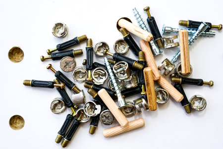 Furniture fittings closeup. A pile of a various assembly fittings on a white laminated chipboard...