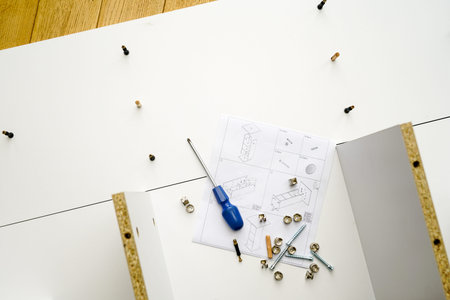 New white laminated chipboard furniture self mounting set with fitting screws, wooden pins, fastenings, screwdrivers and assembly diagramの写真素材