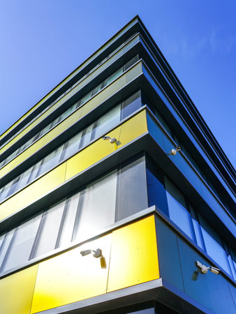 Corner of a modern office building with several surveillance cameras on a blue sky background