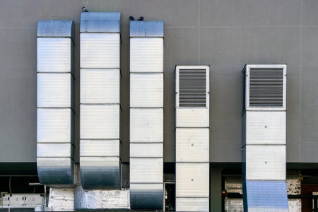 Galvanized tin square ventilation system pipeworks on the background of a gray building wall