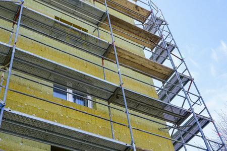 Scaffolding around the facade of the apartment building to perform thermal insulation works with thick mineral rock wool platesの写真素材