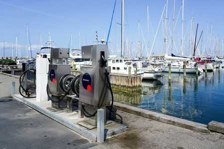 A small gas station for ships and boats on the port with diesel and gasoline filling options, yacht marina with moored sailboatsの写真素材