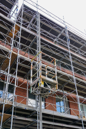 Repair of the facade of a historic tall house using scaffolding with temporary elevator platformの写真素材