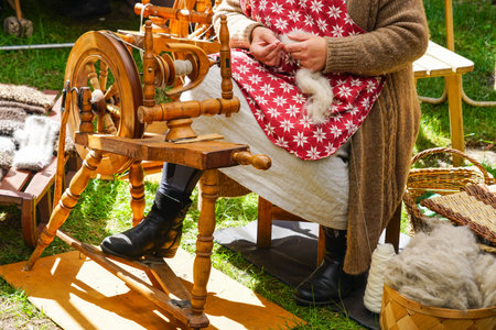 Authentic ancient wooden spinning wheel in action, full yarn basket, a woman at the spinning wheel, woman spinning yarnの写真素材