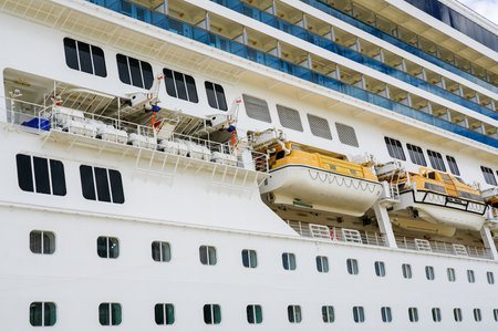 Side view of large white cruise ship with hanging lifeboats and liferafts, emergency rescue boats and self inflating life raftsの写真素材