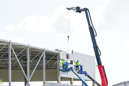Sandwich panels wall assembly using telescopic boom crane and two self propelled articulating boom...