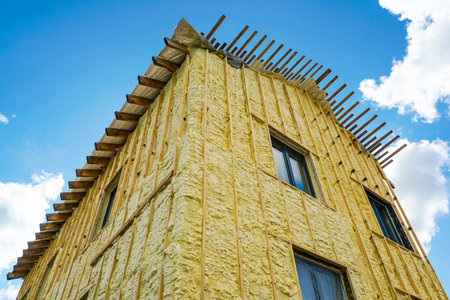 The facade of the residential house sprayed with a layer of polyurethane thermal insulation foam before siding with wooden planks, blue sky backgroundの写真素材