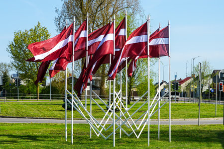 Many national flags of Latvia fluttering in the wind as a decoration of the city during national holidays, blue sky backgroundの写真素材