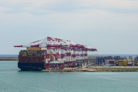 Large, high fully loaded container ship moored at the port container terminal with many high cranesの写真素材