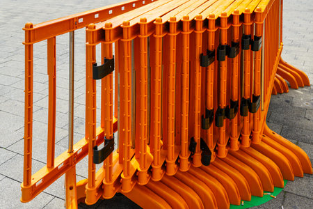 Movable foldable temporary orange plastic lightweight barrier sections for regulating people flow at...