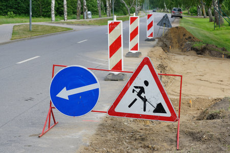 A roadside repair area demarcated by warning and direction road signs and red and white striped posts, warning road signs have been erectedの写真素材