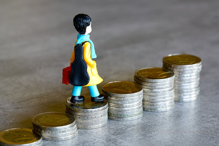 Miniature human figure climbs a staircase made of two euro coins, symbolic of a young persons path...