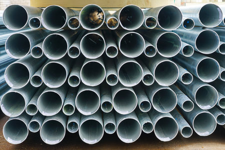 A stack of new tall round conical metallic pipes on wooden pallets at a construction site.の写真素材