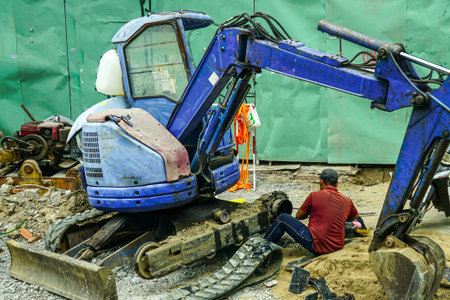 Broken mini excavator on the street, at a work site, on-site repair, primitive bearing replacement,...